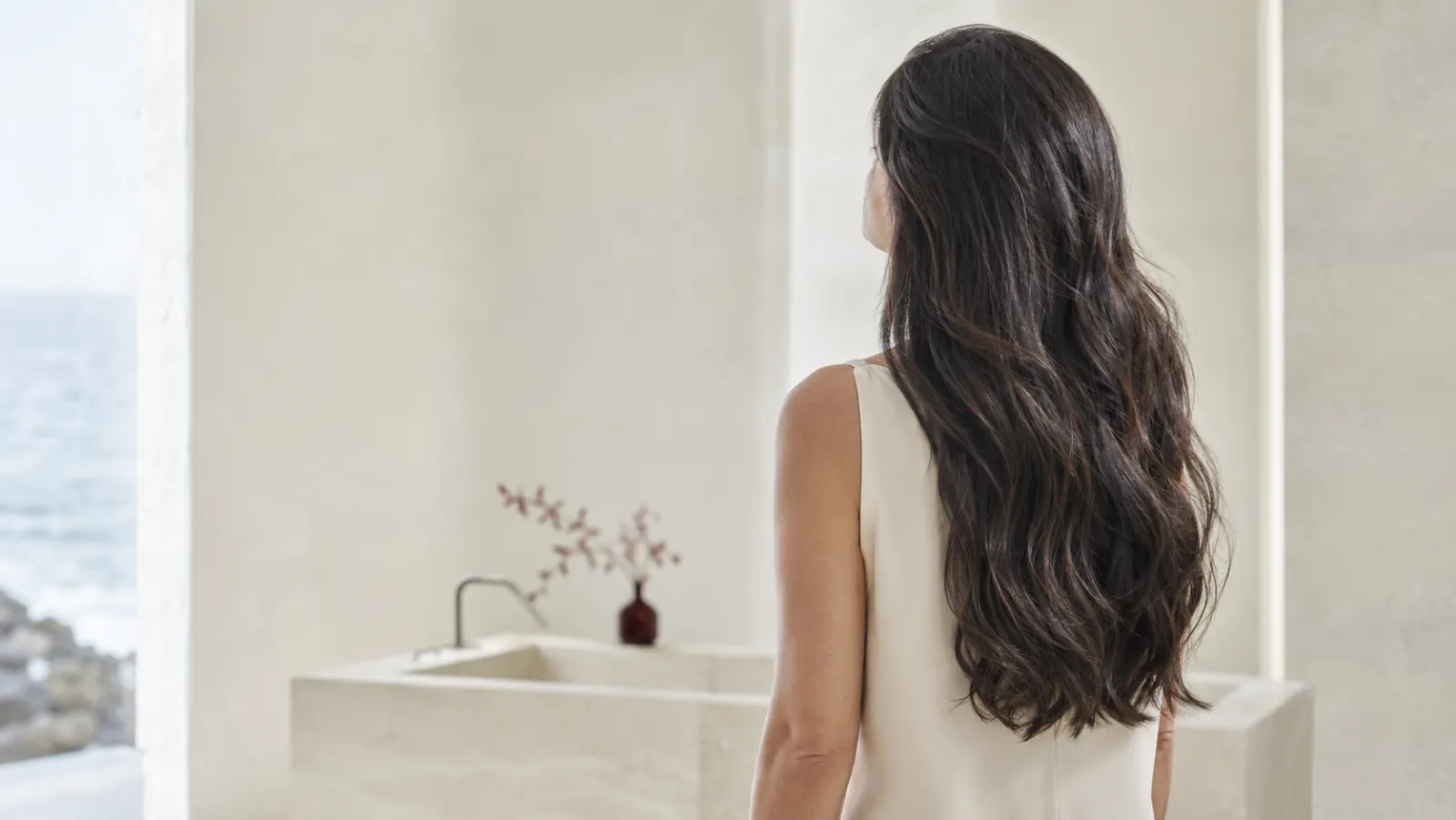 自然な光を受けて艶が際立つ、ゆるやかなウェーブのロングヘアの仕上がりイメージ